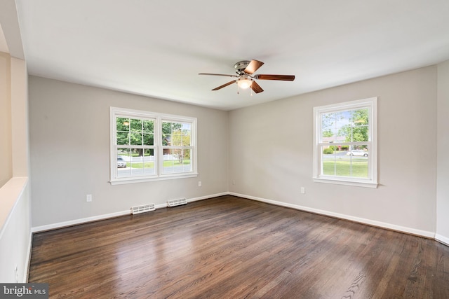 unfurnished room with visible vents, dark wood finished floors, ceiling fan, and baseboards