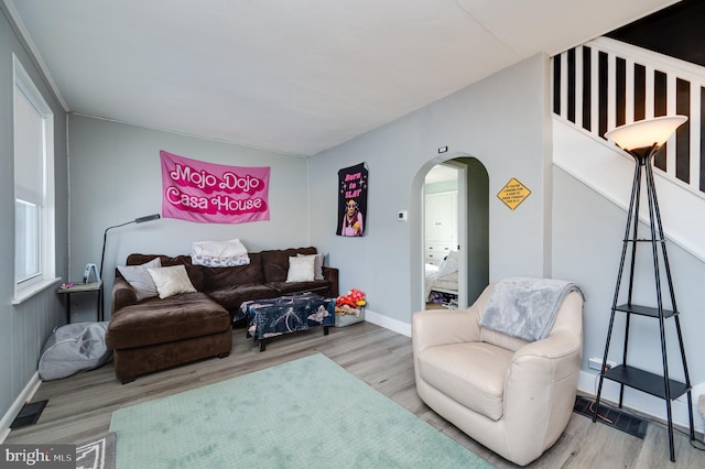 living area with arched walkways, baseboards, visible vents, and wood finished floors