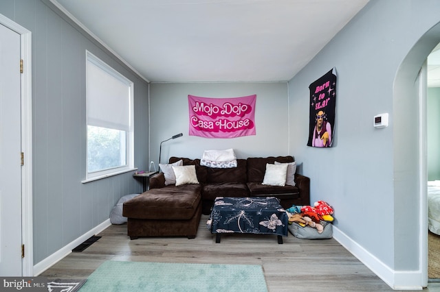 living area with baseboards, arched walkways, and wood finished floors