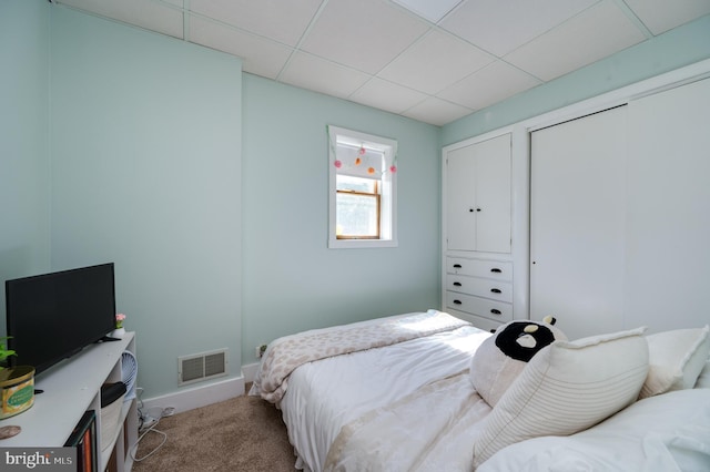 carpeted bedroom with baseboards, visible vents, and a drop ceiling