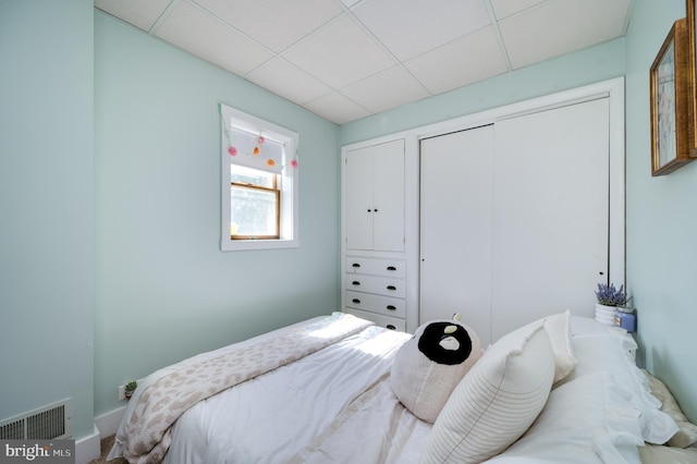 bedroom with visible vents, a paneled ceiling, and a closet