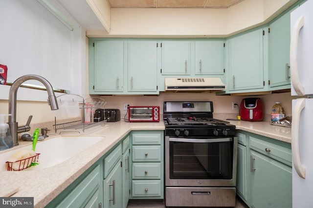 kitchen featuring gas stove, light countertops, exhaust hood, and a sink