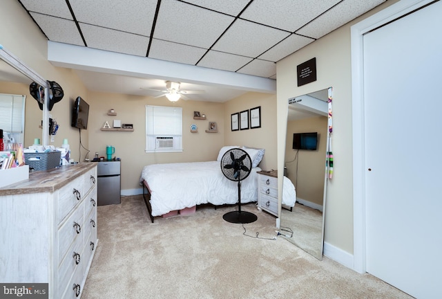 bedroom with baseboards, a drop ceiling, light carpet, and cooling unit