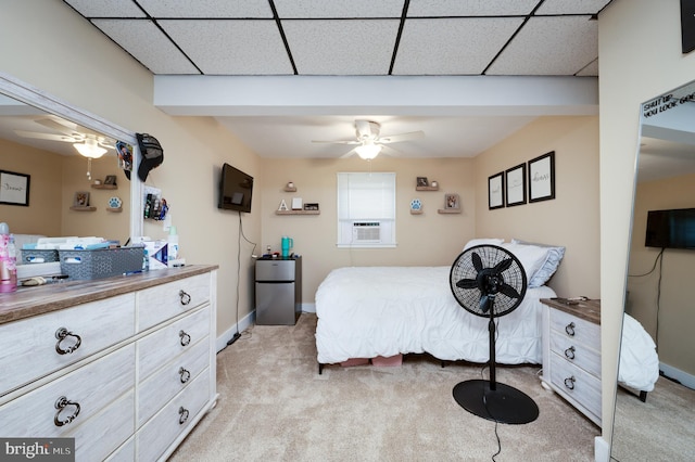bedroom featuring ceiling fan, baseboards, cooling unit, light carpet, and a drop ceiling