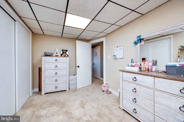 bedroom featuring baseboards, light carpet, and a paneled ceiling