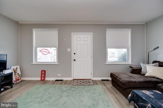 living area with baseboards, ornamental molding, wood finished floors, and visible vents