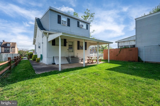 rear view of house with fence, a patio, and a yard
