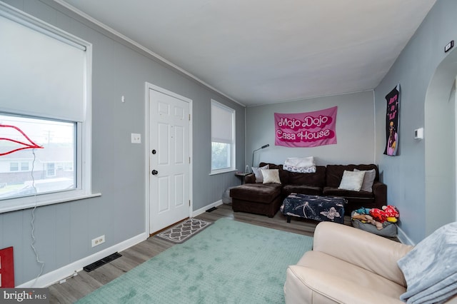 living area featuring baseboards, arched walkways, wood finished floors, and visible vents