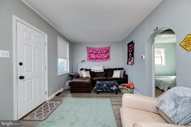 living area featuring baseboards, arched walkways, and wood finished floors