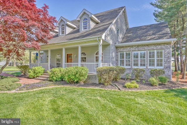 cape cod home featuring covered porch, a shingled roof, and a front lawn