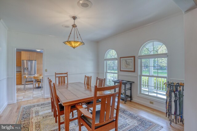 dining room featuring ornamental molding and light wood-style flooring