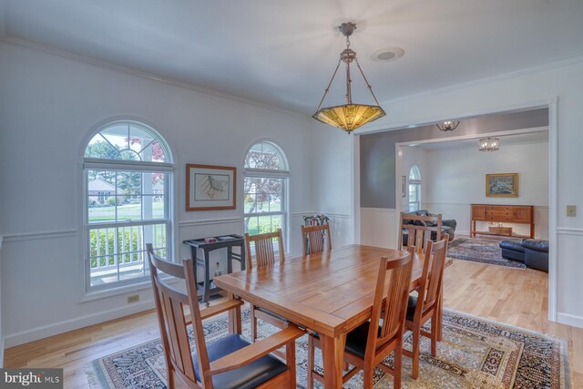 dining space featuring baseboards, ornamental molding, and light wood finished floors