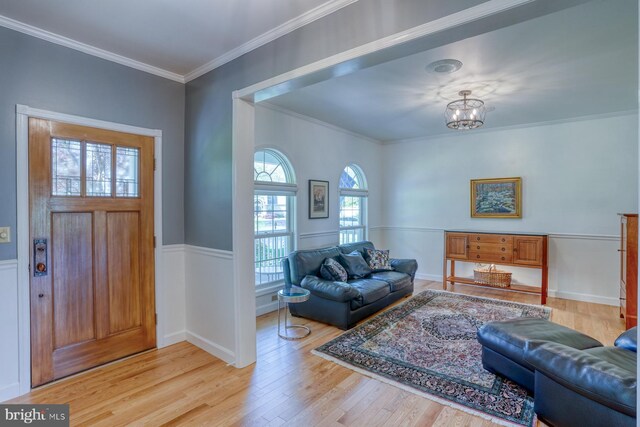 entryway with crown molding, an inviting chandelier, and light wood-type flooring