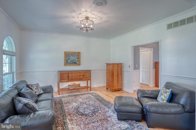 living room featuring crown molding, an inviting chandelier, light wood-style floors, and visible vents