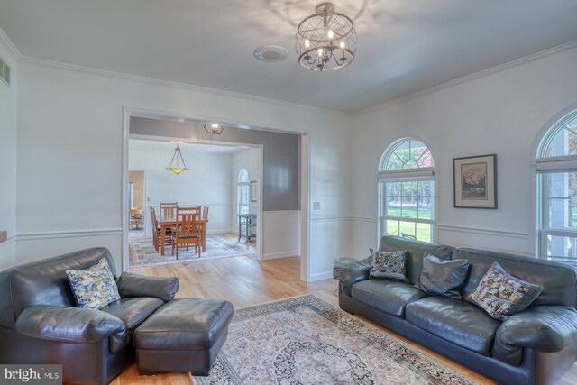 living room featuring crown molding, wood finished floors, a notable chandelier, and visible vents