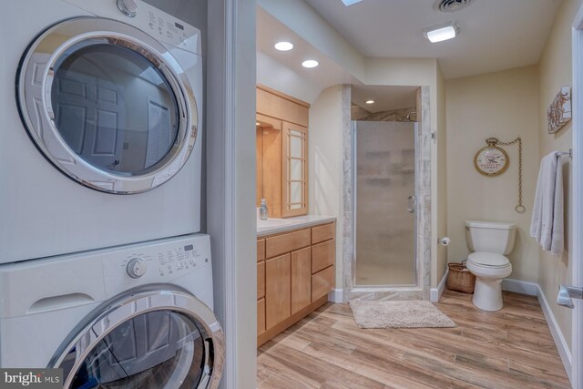 washroom with laundry area, baseboards, recessed lighting, light wood-type flooring, and stacked washer / drying machine