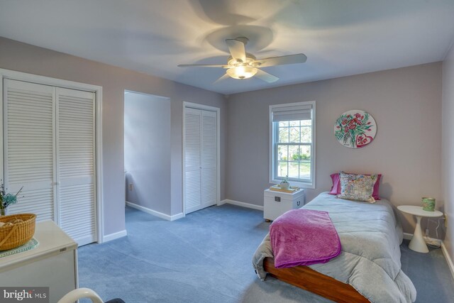 bedroom with baseboards, multiple closets, ceiling fan, and light carpet