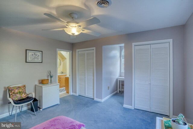 bedroom with a ceiling fan, visible vents, baseboards, multiple closets, and carpet flooring