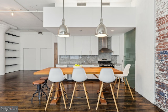 kitchen featuring white cabinets, dark wood finished floors, wall chimney exhaust hood, and visible vents