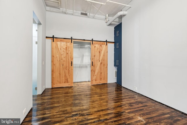 interior space featuring visible vents, a barn door, and wood finished floors