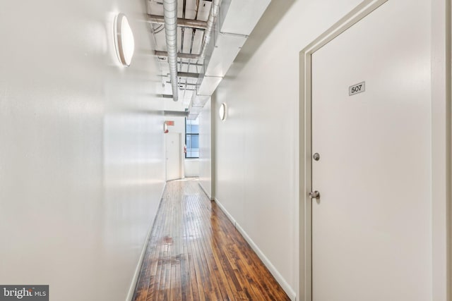 hallway featuring wood-type flooring and baseboards