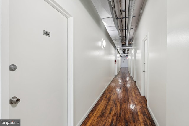 corridor with baseboards and hardwood / wood-style floors