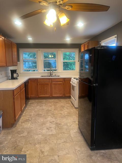 kitchen featuring a ceiling fan, a sink, brown cabinets, black appliances, and light countertops