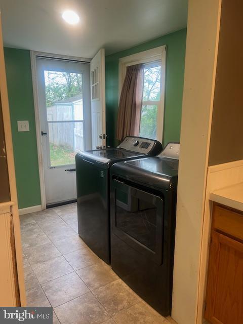 clothes washing area featuring independent washer and dryer, baseboards, light tile patterned flooring, and laundry area