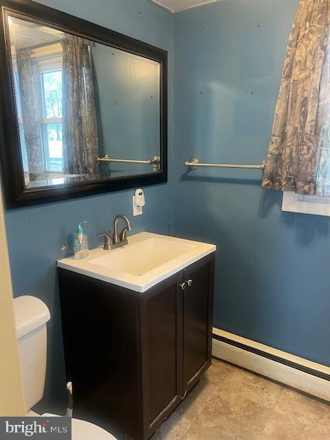 bathroom featuring toilet, a baseboard radiator, vanity, and baseboards