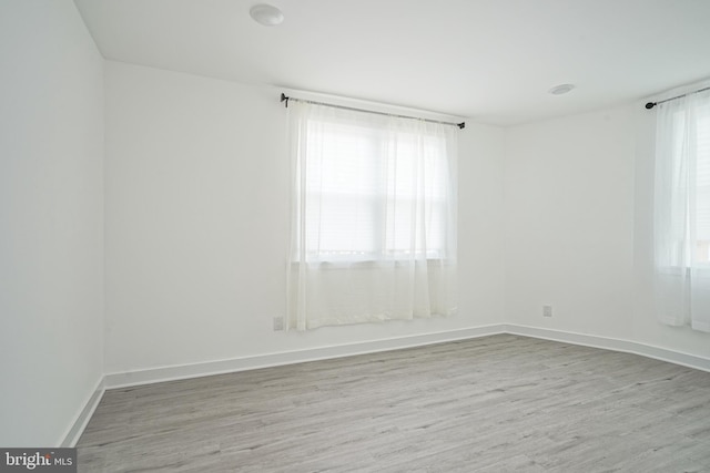spare room featuring baseboards and wood finished floors