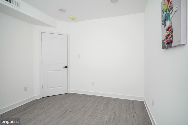 spare room featuring baseboards, visible vents, and wood finished floors