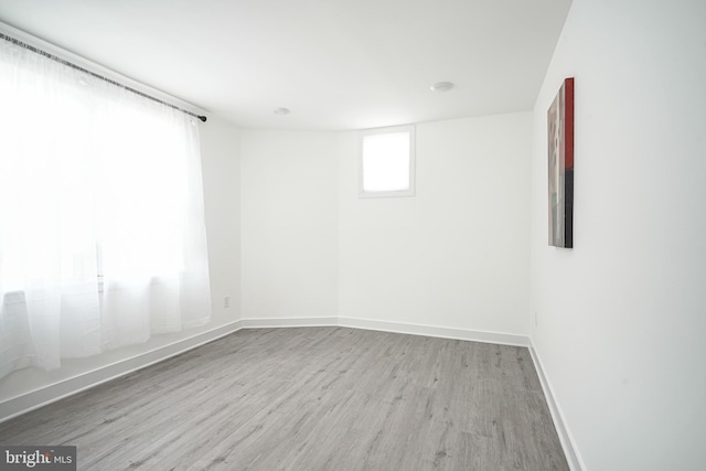 spare room with baseboards and wood finished floors