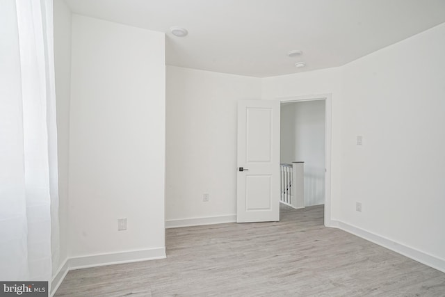 spare room with baseboards and light wood-style flooring