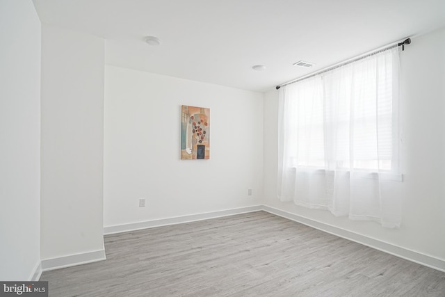 empty room featuring baseboards, visible vents, and wood finished floors