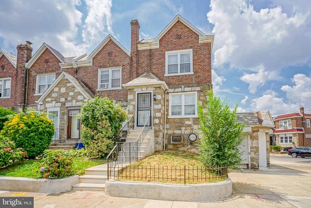 multi unit property featuring brick siding, driveway, a chimney, and stone siding