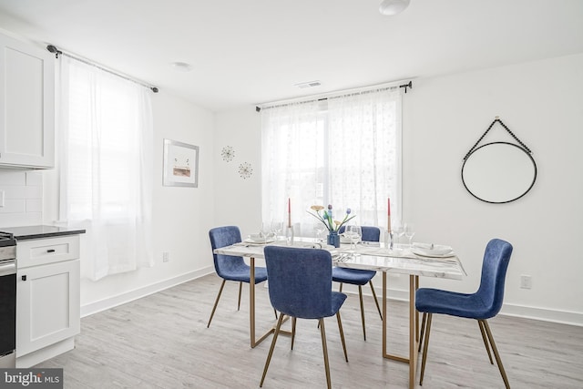 dining area featuring baseboards, visible vents, and light wood finished floors