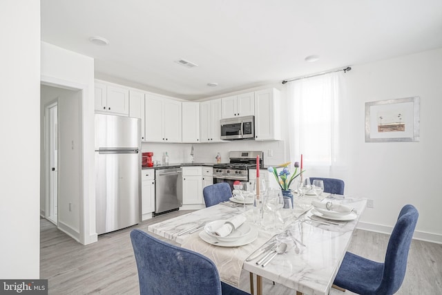 kitchen with visible vents, appliances with stainless steel finishes, baseboards, light wood-style floors, and white cabinetry