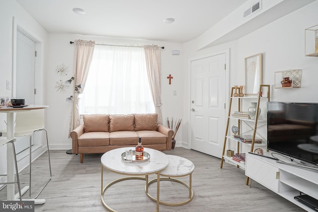 living area featuring baseboards, visible vents, and light wood-type flooring