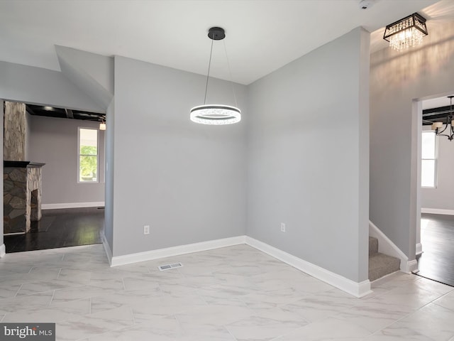 unfurnished dining area with baseboards, visible vents, marble finish floor, and a notable chandelier