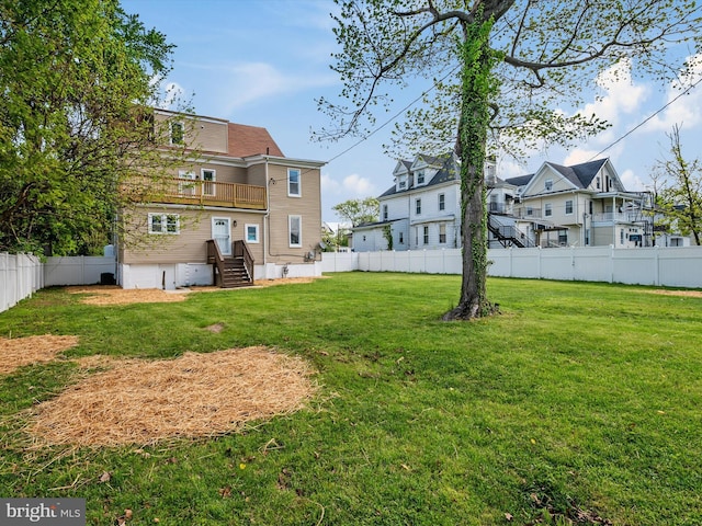 view of yard with a fenced backyard, a balcony, and a residential view