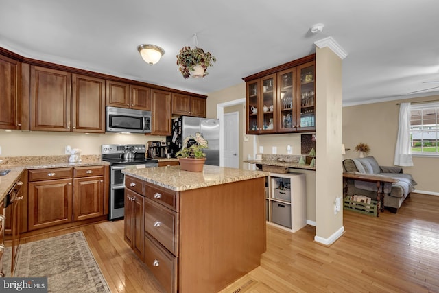 133 Teal Dr, Pasadena, MD 21122 - kitchen featuring appliances with stainless steel finishes, light wood-style flooring, glass insert cabinets, light stone counters, and a kitchen island