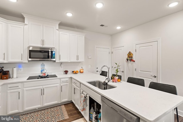 10424 Ratcliffe Trl, Manassas, VA 20110 - kitchen featuring dark wood finished floors, a sink, a peninsula, white cabinets, and appliances with stainless steel finishes