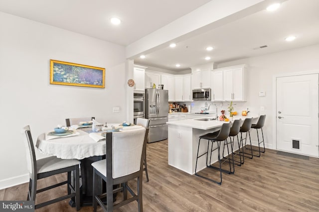 10424 Ratcliffe Trl, Manassas, VA 20110 - kitchen featuring a peninsula, white cabinetry, appliances with stainless steel finishes, and a breakfast bar