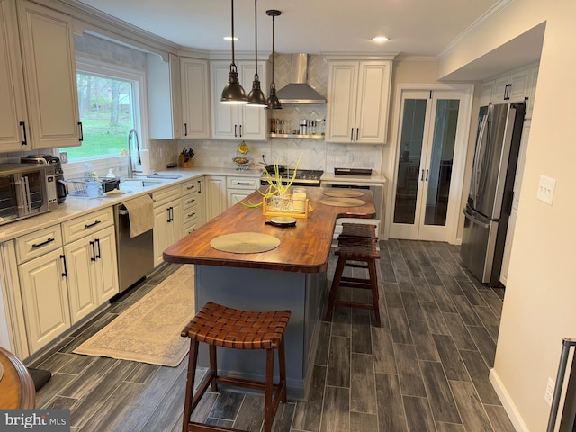 1301 Kelly Ct, Herndon, VA 20170 - kitchen with stainless steel appliances, butcher block counters, wall chimney exhaust hood, dark wood-style flooring, and a sink