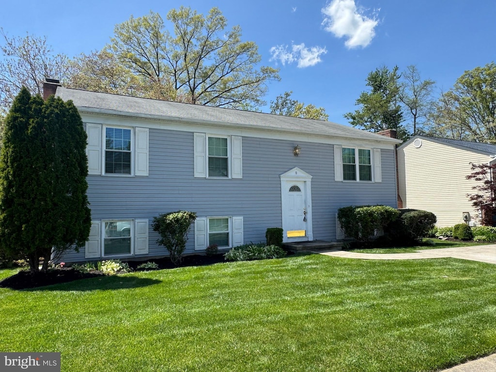 bi-level home featuring a chimney and a front yard