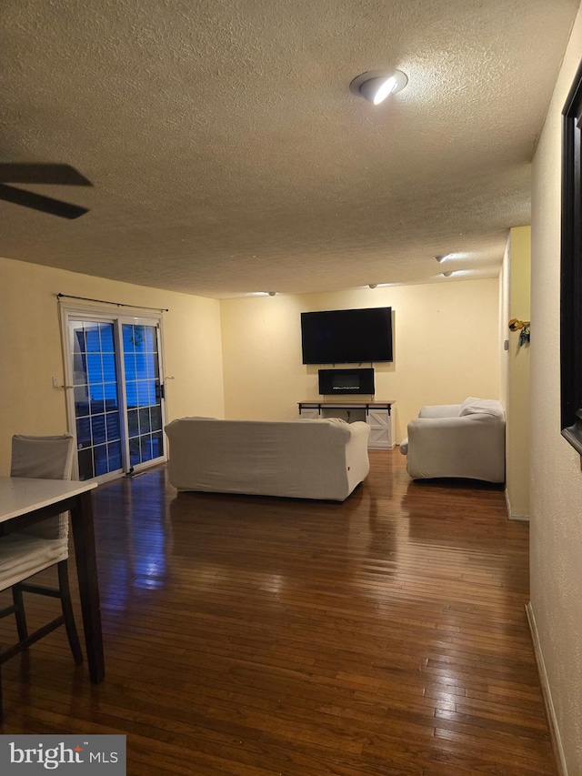 living area featuring baseboards, hardwood / wood-style flooring, and a textured ceiling