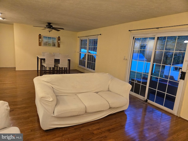 living room with a textured ceiling, ceiling fan, and wood finished floors