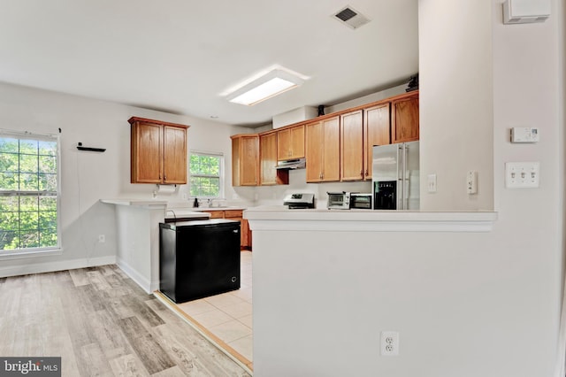 kitchen featuring visible vents, high end refrigerator, light countertops, a peninsula, and under cabinet range hood