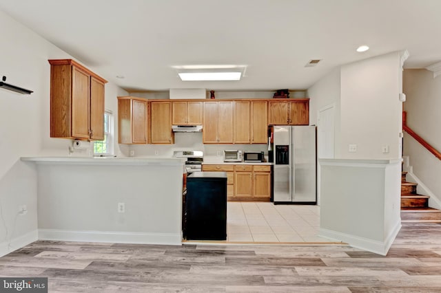 kitchen with appliances with stainless steel finishes, light countertops, light wood finished floors, a peninsula, and under cabinet range hood
