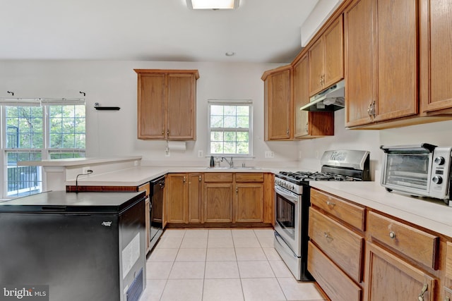 kitchen with a peninsula, black dishwasher, stainless steel gas range, under cabinet range hood, and a sink